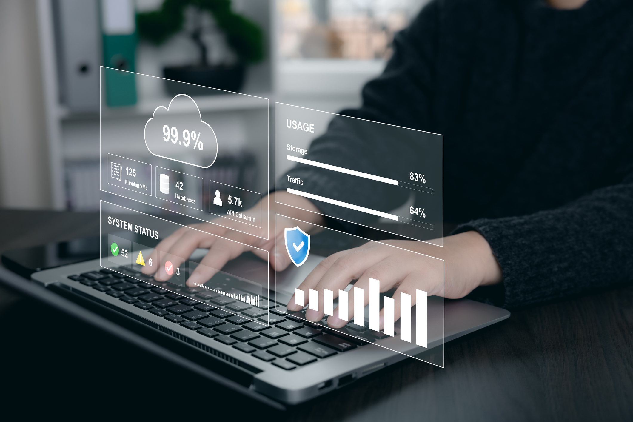 Person using laptop with virtual cloud dashboard showing system status, storage, traffic, running VMs, databases, API calls, and uptime metrics for cloud operations and infrastructure monitoring.